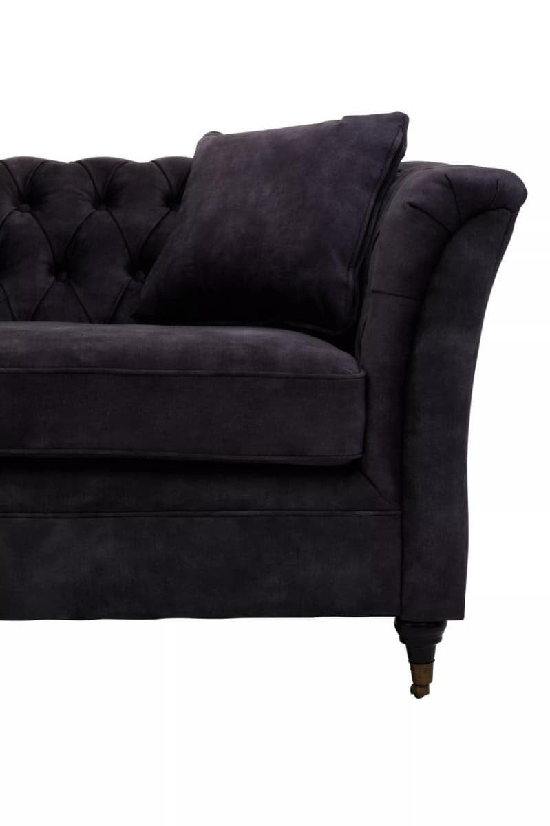 Three-seat sofa upholstered in grey velvet with a tufted backrest and curved armrests, featuring a decorative throw pillow and elegant wooden legs