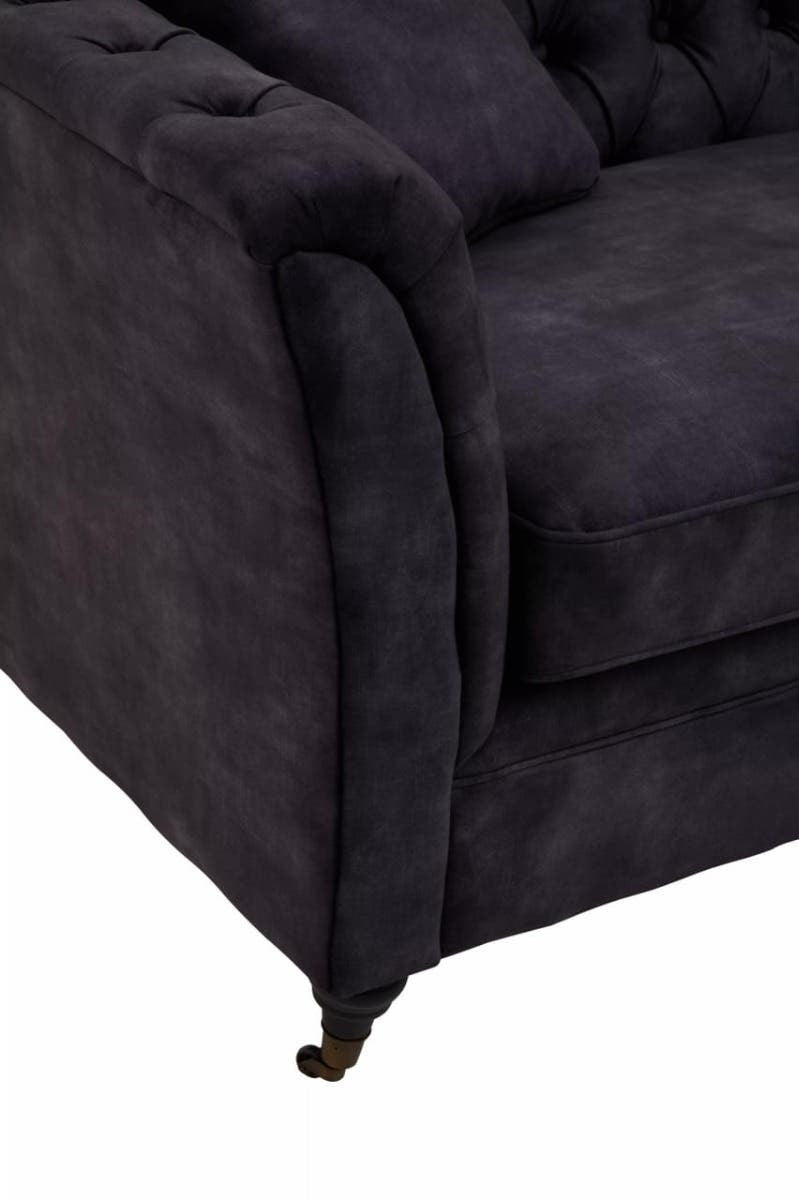 Grey velvet sofa with a three-seat design, featuring a tufted backrest and plush cushions. The armrest has a rounded shape, and the sofa is supported by sleek, gold-colored legs. The fabric has a soft texture, enhancing the overall luxurious appearance