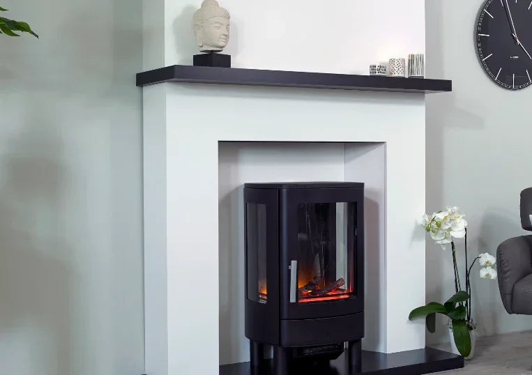 Black electric stove fire with glass sides set in modern white fireplace surround