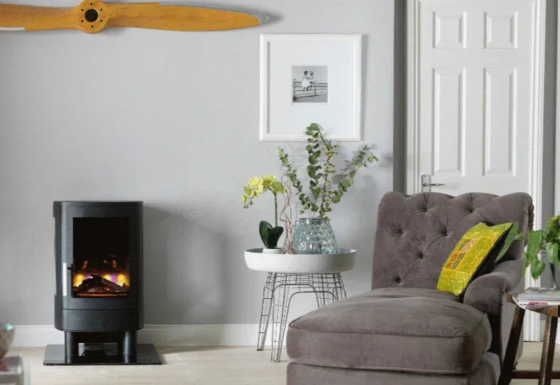 Grey upholstered chaise lounge with cushion near electric fireplace in living room