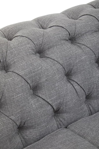 Close-up view of the tufted grey linen upholstery on the Stella three-seat sofa, showcasing the soft texture and button detailing