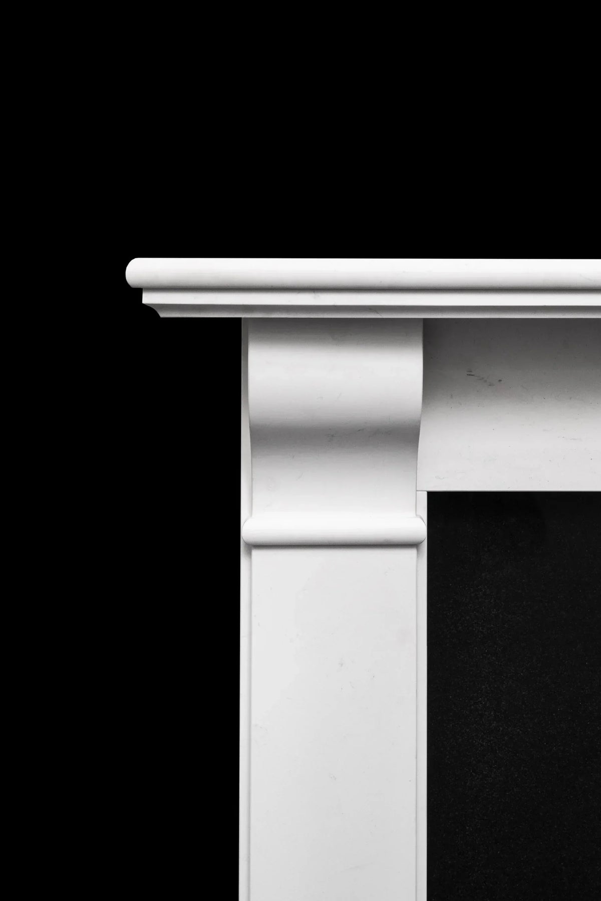 White marble fireplace surround close-up showing smooth column detail against black backdrop