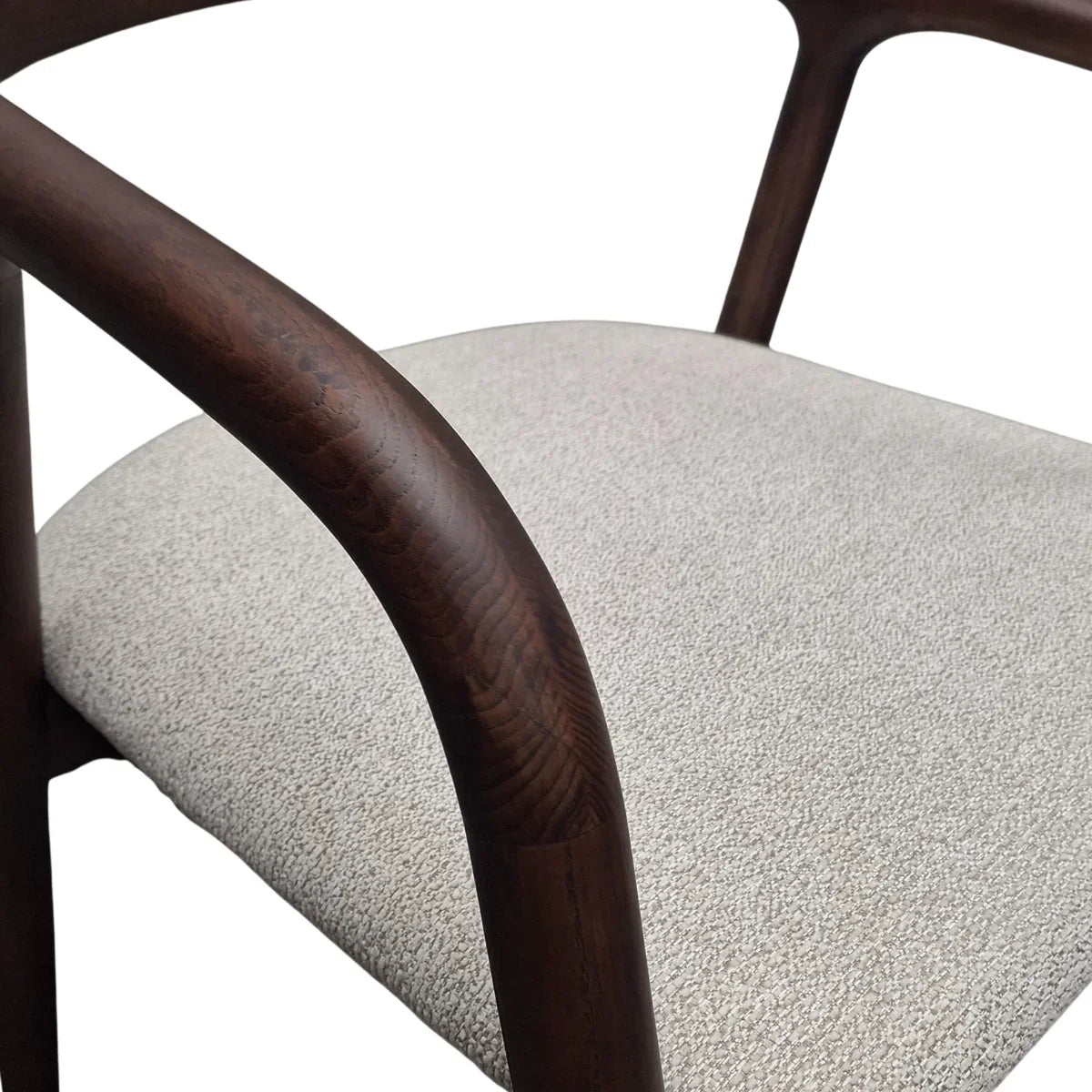 Closeup of white fabric dining chair seat with curved dark wood armrest