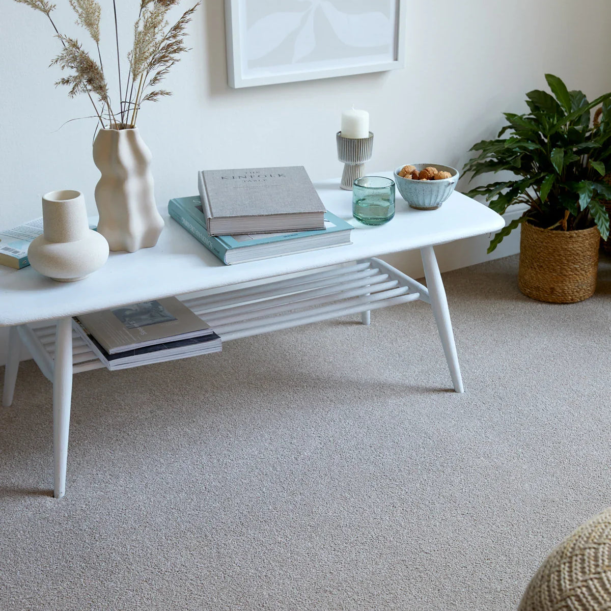 White coffee table with tapered legs styled with books and decor in a cozy living room setting