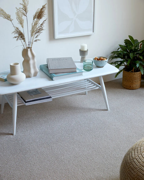 White coffee table with tapered legs styled with books and decor in a cozy living room setting