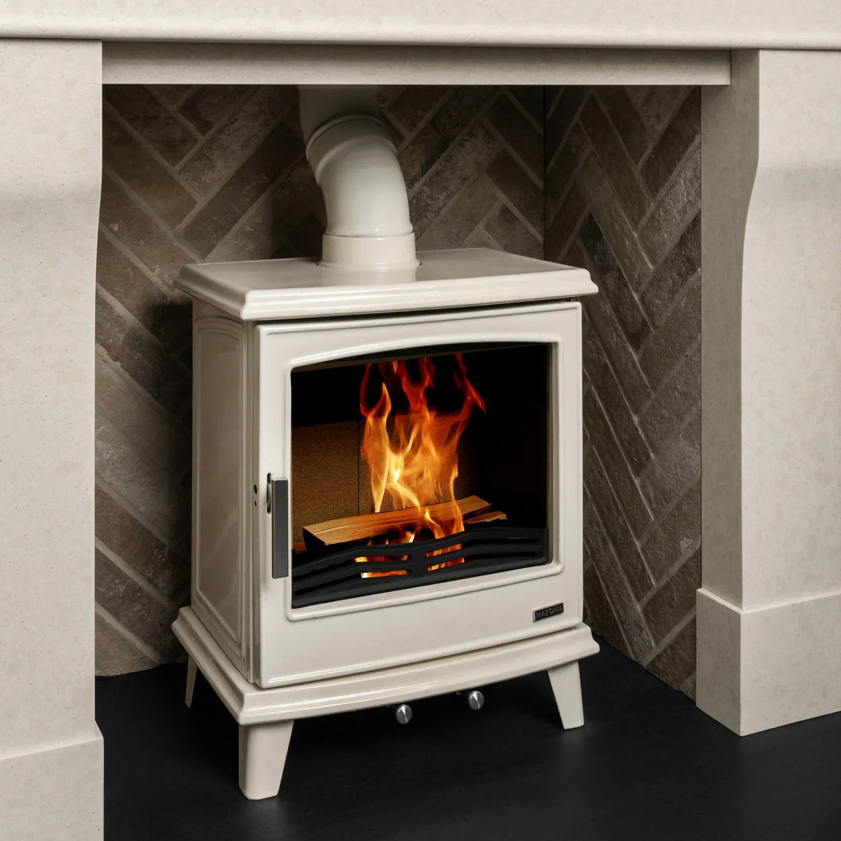 cream wood burning stove with fire, side angle view, set against herringbone tile surround
