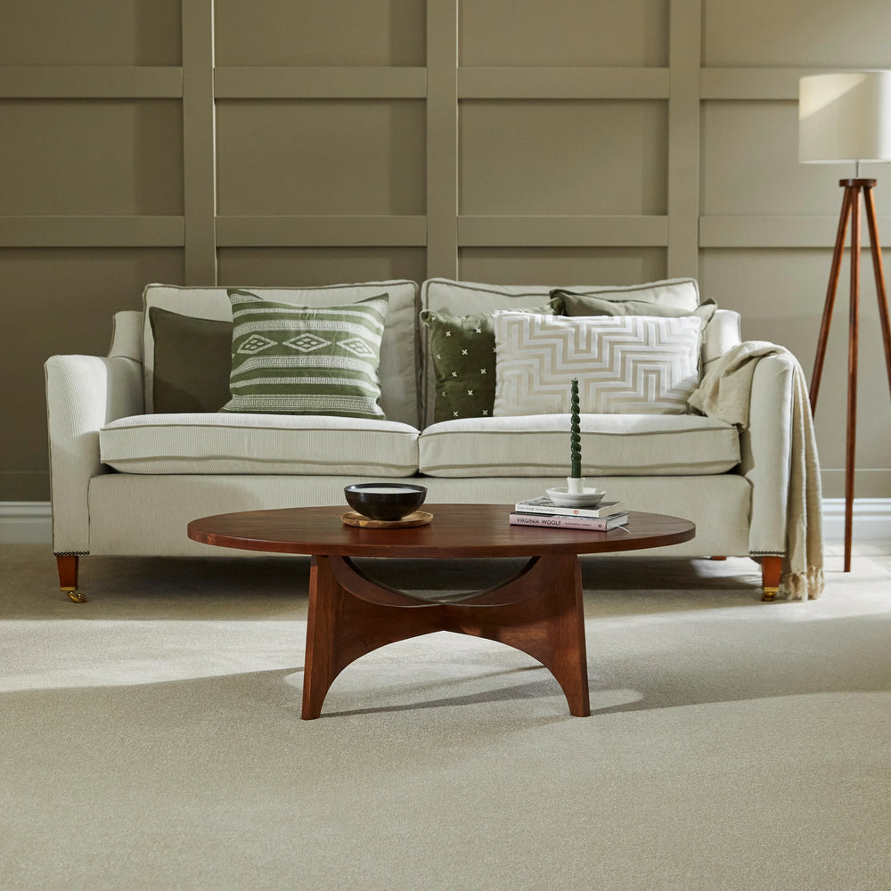 Light grey sofa with patterned cushions in a paneled living room, paired with a wooden coffee table.