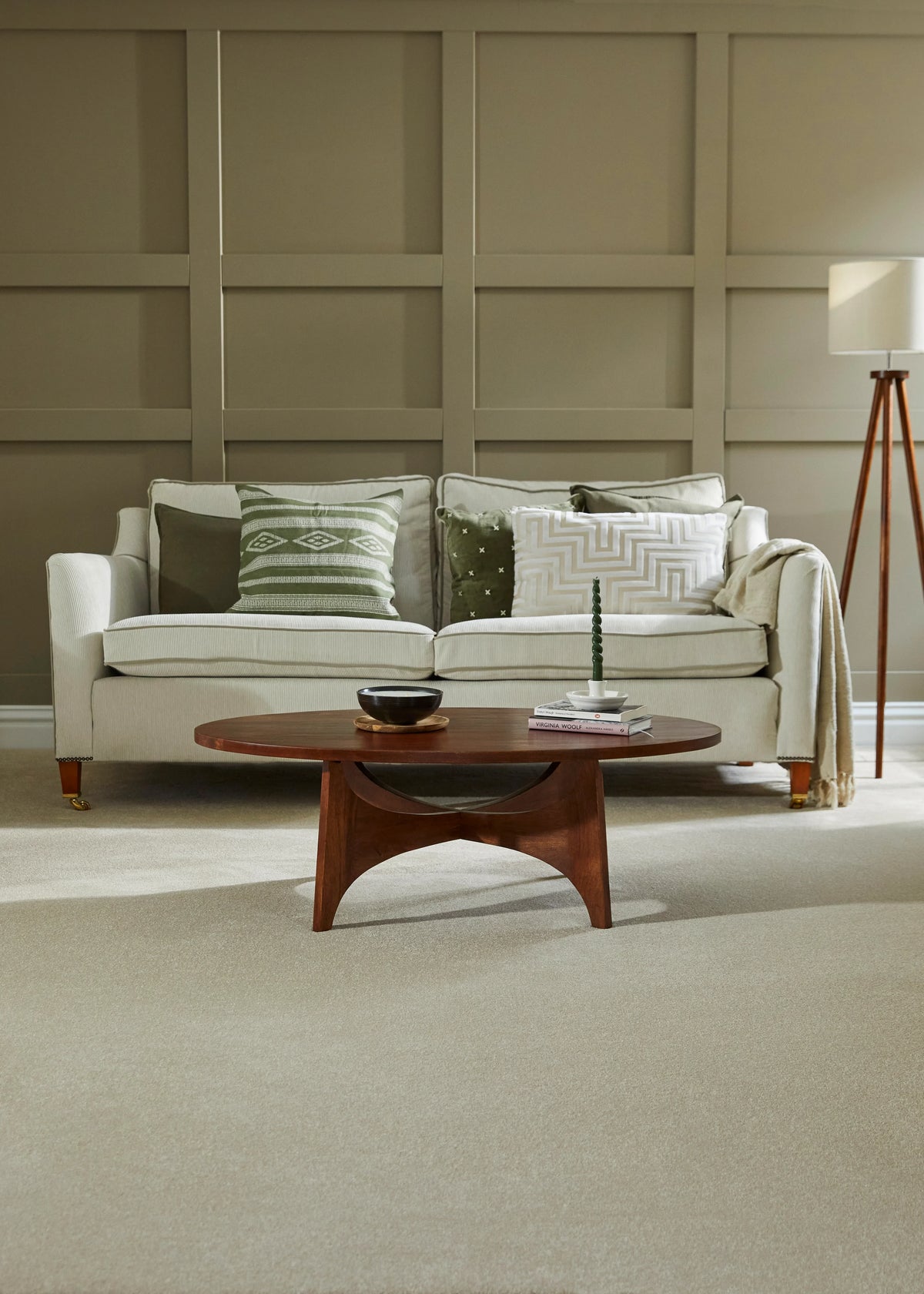 Light grey sofa with patterned cushions in a paneled living room, paired with a wooden coffee table.