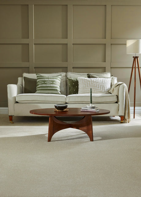 Light grey sofa with patterned cushions in a paneled living room, paired with a wooden coffee table.