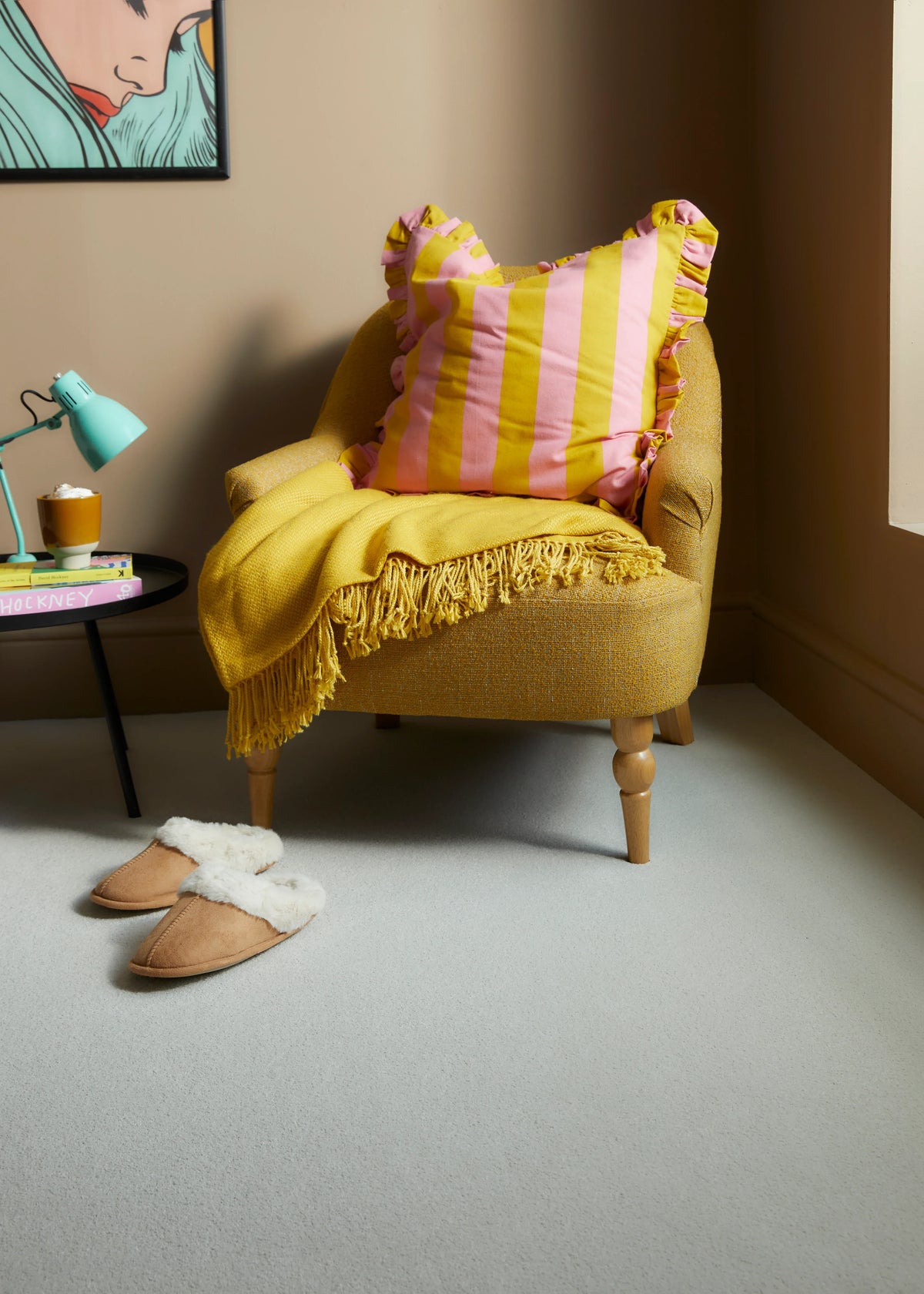 Yellow upholstered armchair with pink striped cushion and fringed throw in cozy room setting