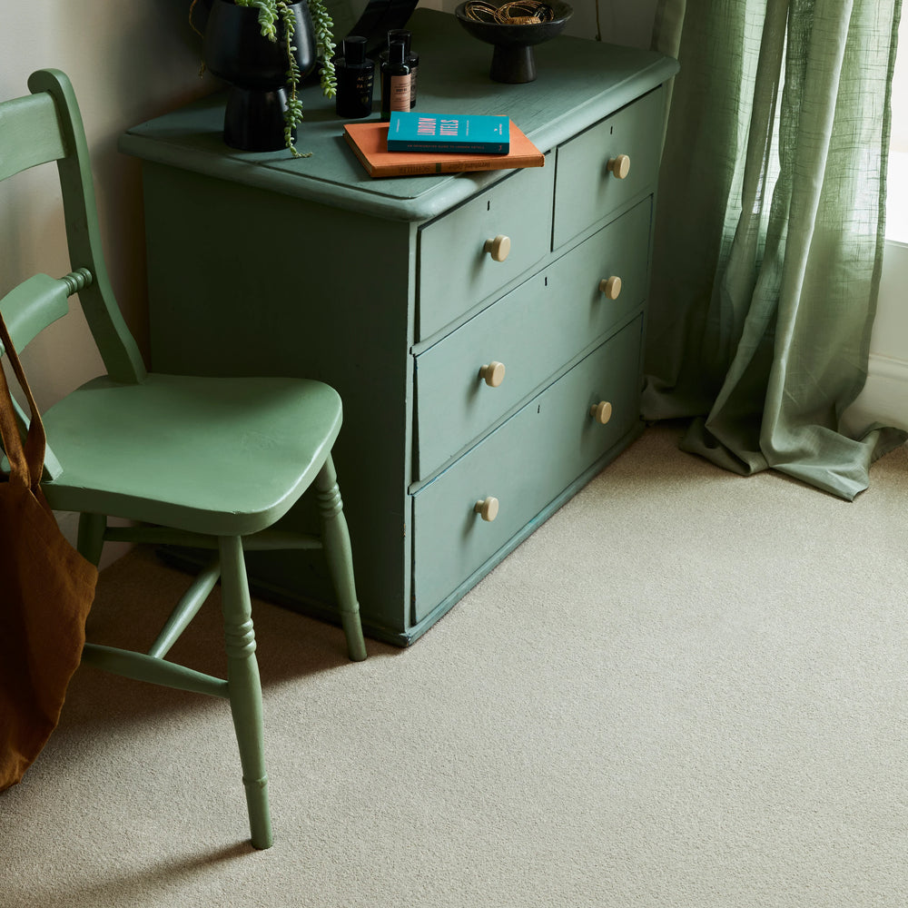 Sage green wooden dresser and chair in a softly lit room with sheer green curtains